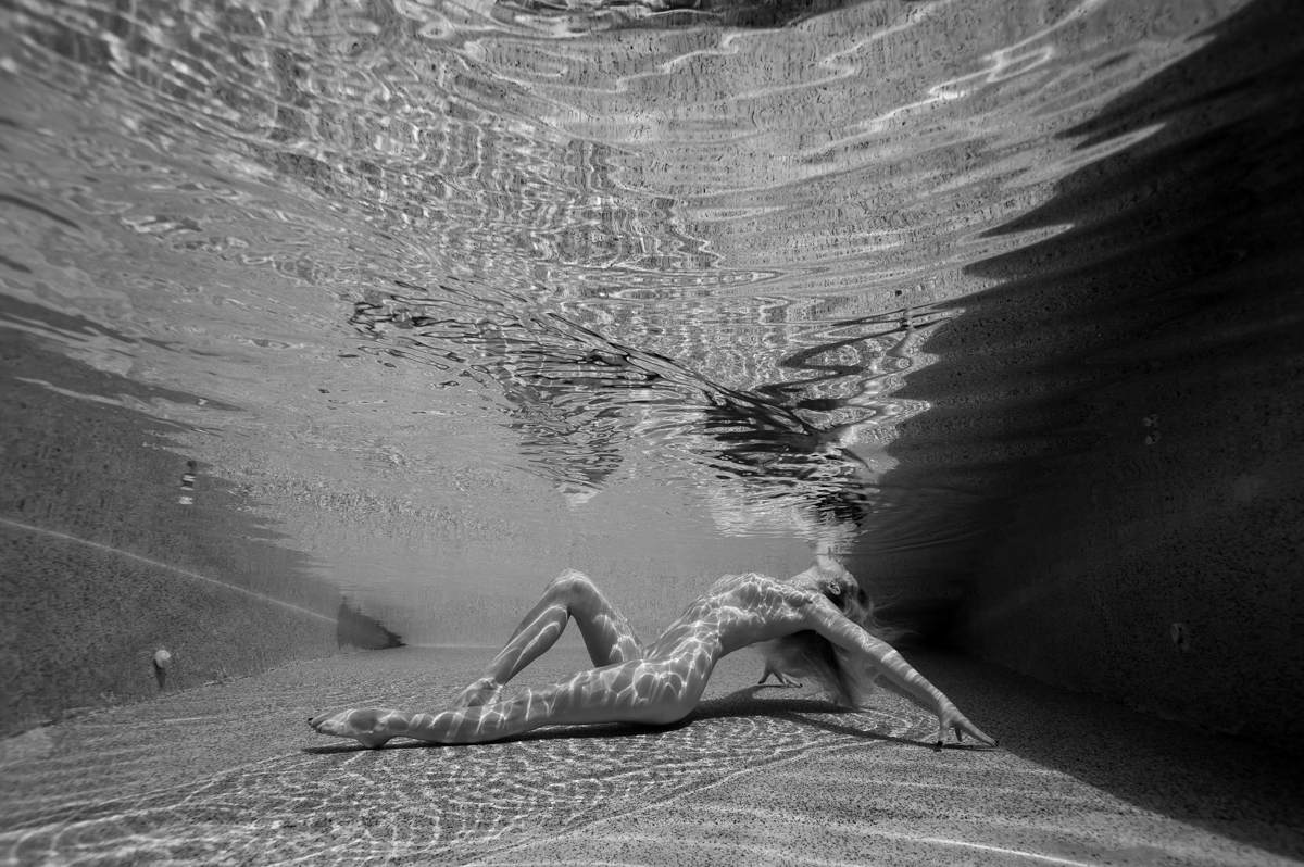 Underwater Fine Art image of nude female arching towards the water surface and almost kissing the surface