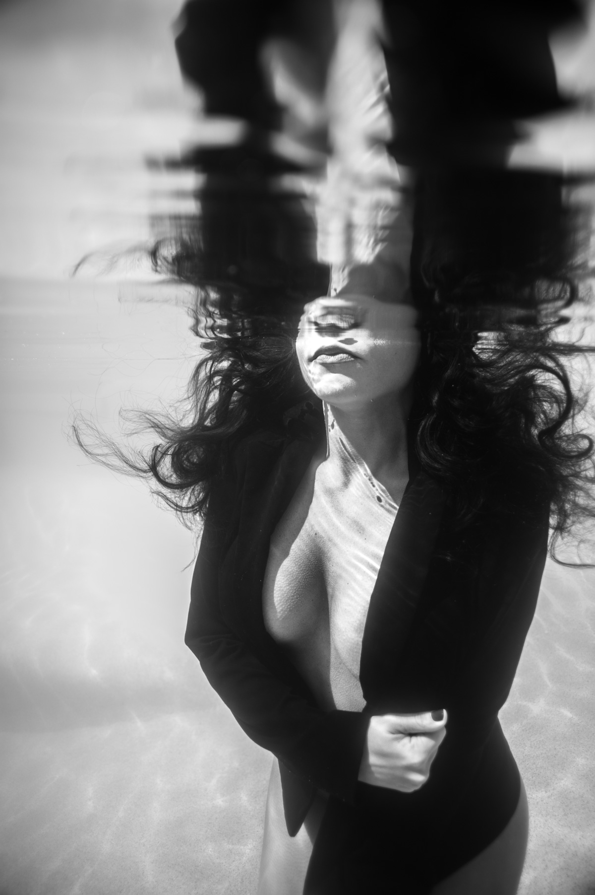 Underwater Fine Art image of nude female wearing a black blazer and kissing the water surface